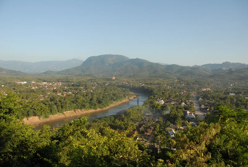 Aerial view from Mount Phousi over the Nam Khan river, town rooftops and forested hills in Luang Prabang.