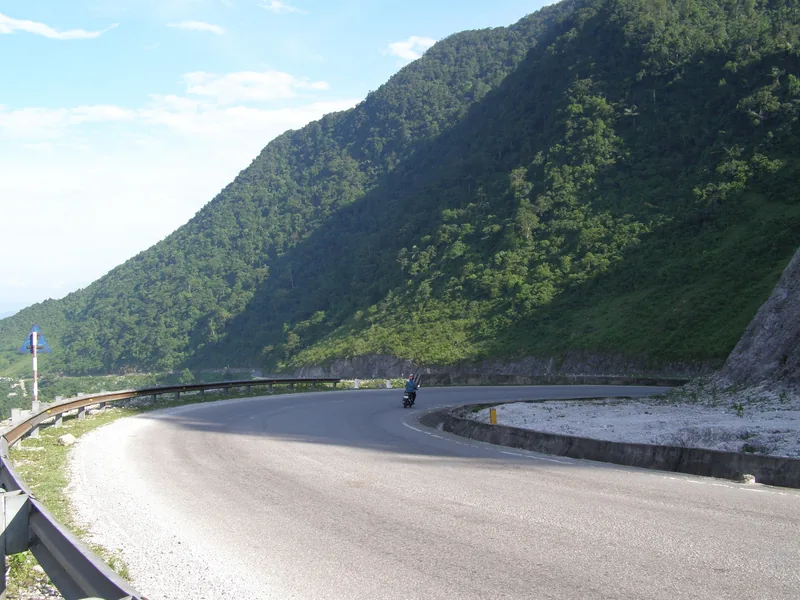 A motorbike rounds a curving mountain pass road near Mai Chau, Vietnam.