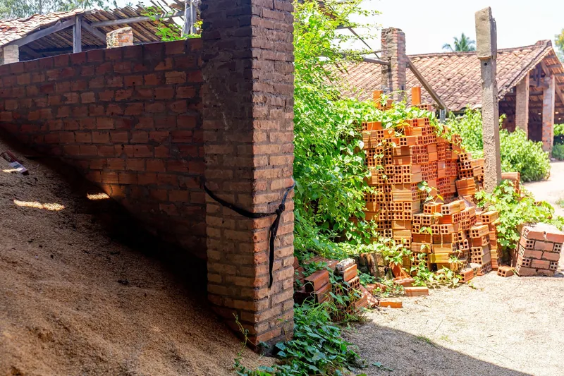 Stacks of red bricks and rustic tiled-roof kilns at a traditional brick factory in the Mekong Delta.