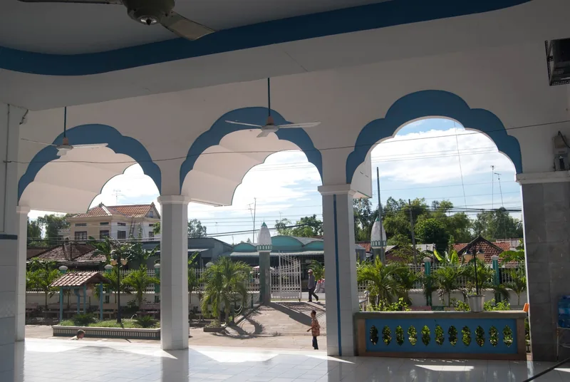 Scalloped blue-and-white arches frame a courtyard view at a mosque in the Mekong Delta.