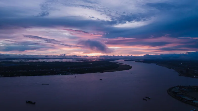 Aerial view of the Mekong River winding through the delta under a vivid pink and blue sunset sky.