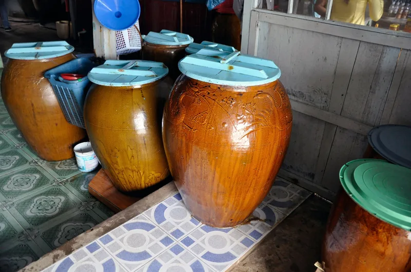 Large glazed clay jars used for fish sauce fermentation stand in a workshop in the Mekong Delta.