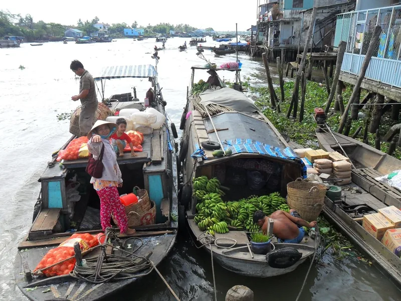 Vendors and boats loaded with tomatoes and bananas gather at a floating market in the Mekong Delta.