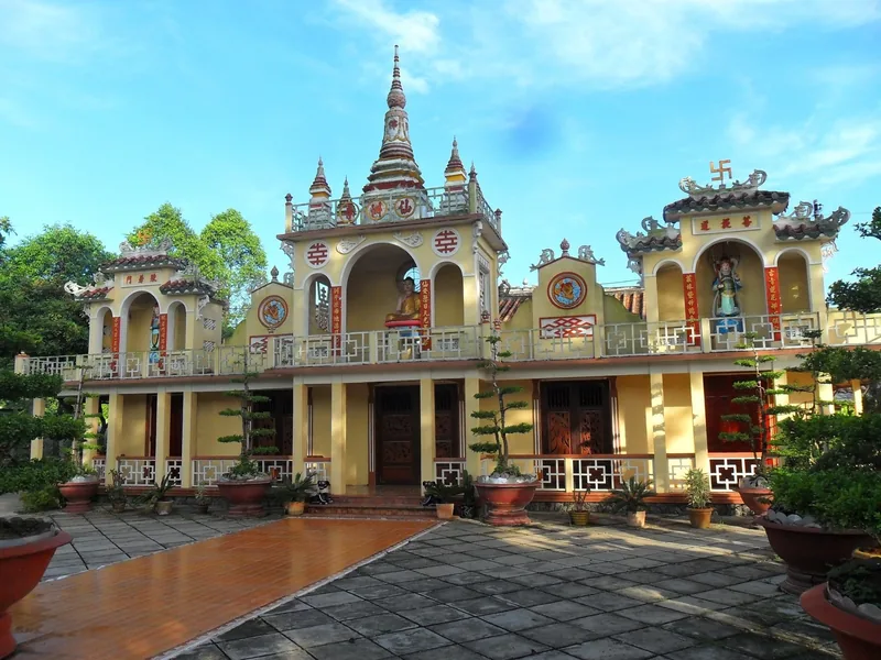 A yellow Buddhist pagoda with ornate towers and bonsai trees in the Mekong Delta.