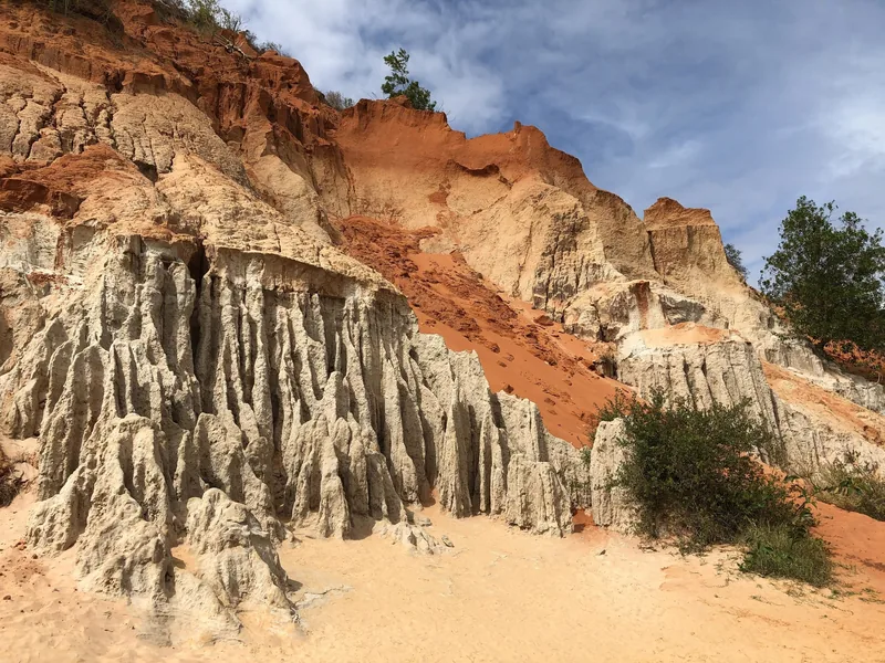 Jagged sandstone formations and red cliffs rise above the sandy path at Fairy Stream in Mui Ne.