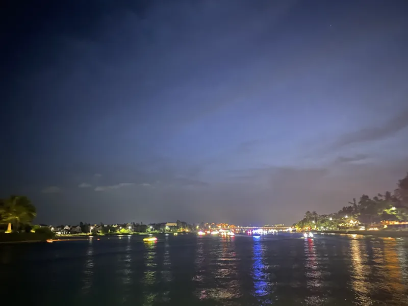 Twilight sky over the Hoai River in Hoi An with reflected lights from riverside restaurants and boats.