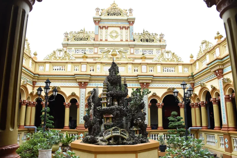 Ornate courtyard of a Mekong Delta temple with a decorative rock garden and colorful mosaic facade
