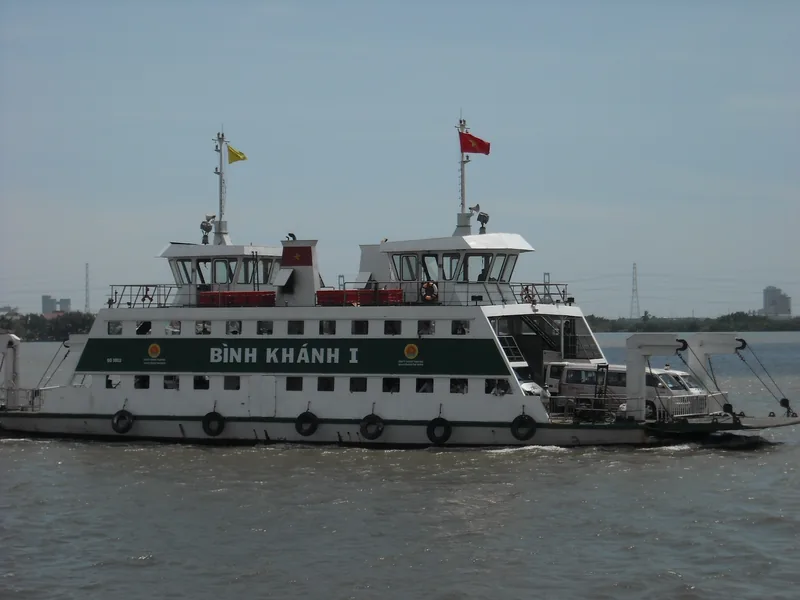 The Binh Khanh I car ferry crosses a wide river in the Mekong Delta with trucks aboard.