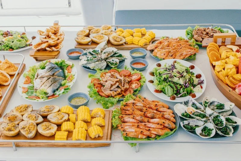 A seafood buffet spread with grilled prawns, oysters, fish, corn and salads on a Nha Trang cruise table.