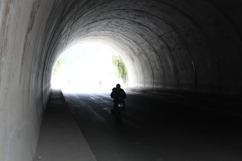 A motorbike rider silhouetted while passing through a concrete tunnel in Ninh Binh.