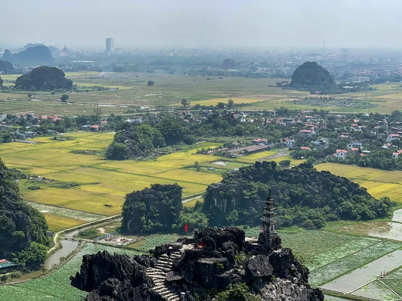 Aerial view from Hang Mua summit over rice paddies, limestone karsts and a small dragon pagoda in Ninh Binh.