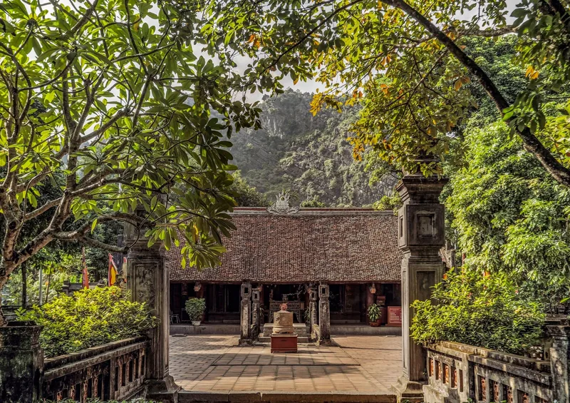 A traditional tiled-roof temple sits amid limestone karst mountains and lush greenery at Hoa Lu ancient capital.