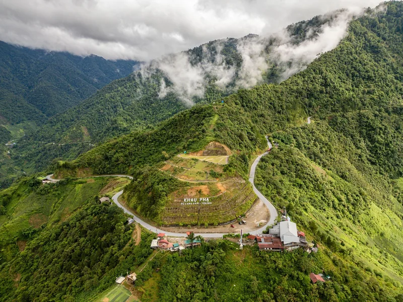 Aerial view of the winding road over Khau Pha Pass through misty green mountains in Mu Cang Chai.