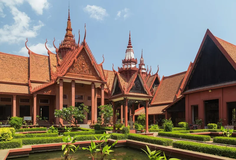 Terracotta courtyard of the National Museum of Cambodia in Phnom Penh with ornate tiered roofs and manicured gardens.