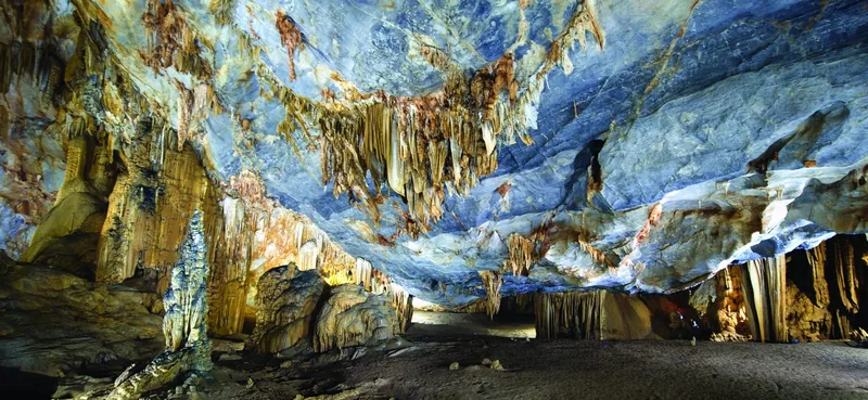 Illuminated stalactites and stalagmites create dramatic formations inside Paradise Cave (Thien Duong Cave).