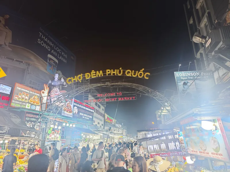 Illuminated arch entrance to Phu Quoc Night Market crowded with visitors under bright signage at night