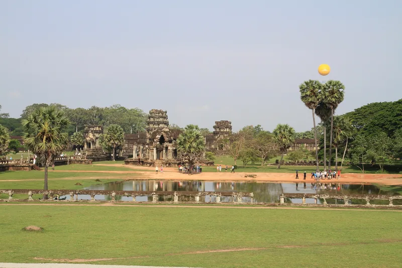 Ancient temple ruins and palm trees surround a reflecting pond near Angkor Wat in Siem Reap.