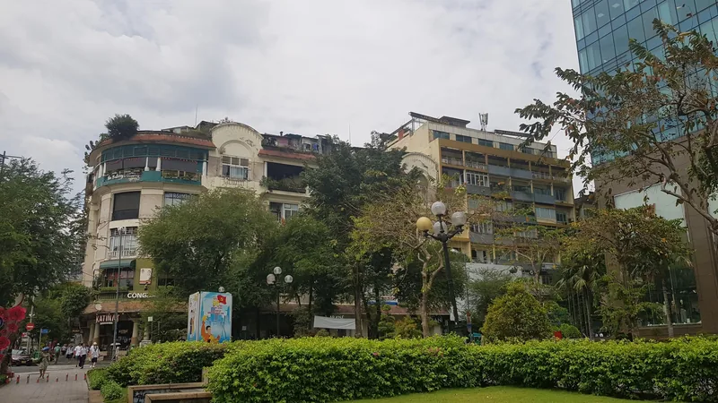 Old apartment buildings with rooftop plants stand behind a green park in Ho Chi Minh City.