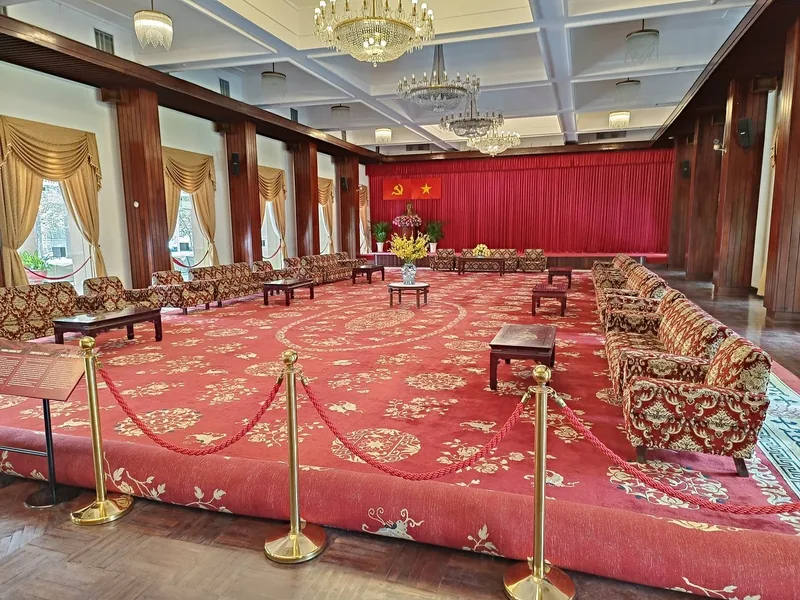 Grand reception hall with red carpet, ornate sofas and chandeliers at the Independence Palace in Saigon.