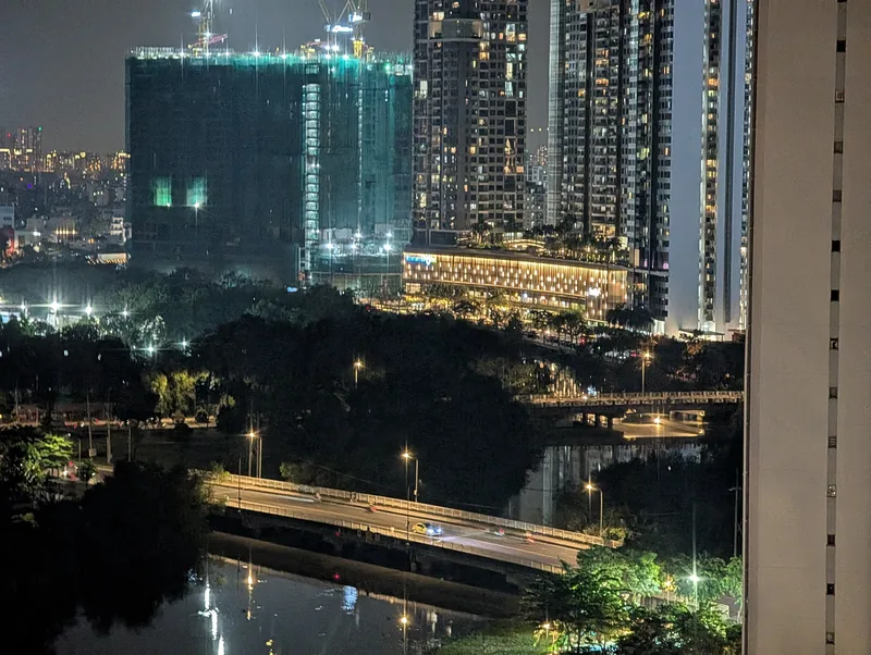 High-rise towers and a bridge glow at night over a canal in Ho Chi Minh City's District 7.