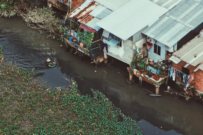 An aerial view shows tin-roofed houses and a small boat along a canal in Ho Chi Minh City.