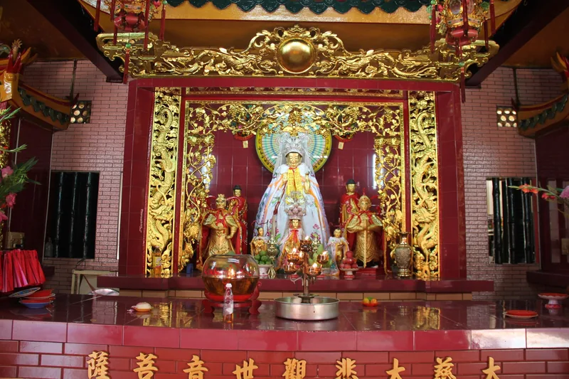 Ornate red and gold altar with a goddess statue at Quan Am Pagoda in Ho Chi Minh City.