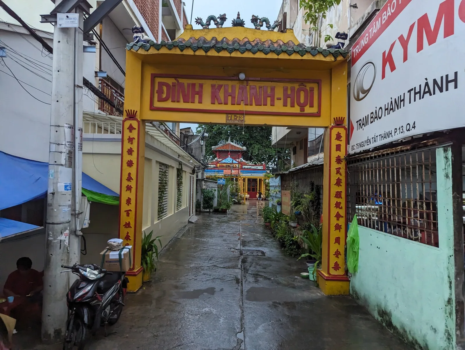 Yellow entrance gate of Đình Khánh Hội communal temple on a narrow street in Ho Chi Minh City.