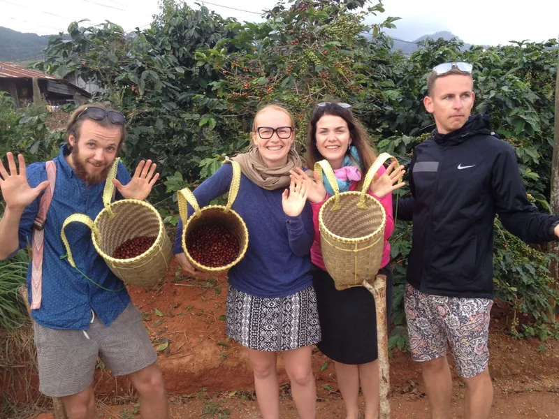 Tourists hold woven baskets of freshly picked coffee cherries on a countryside farm near Da Lat.