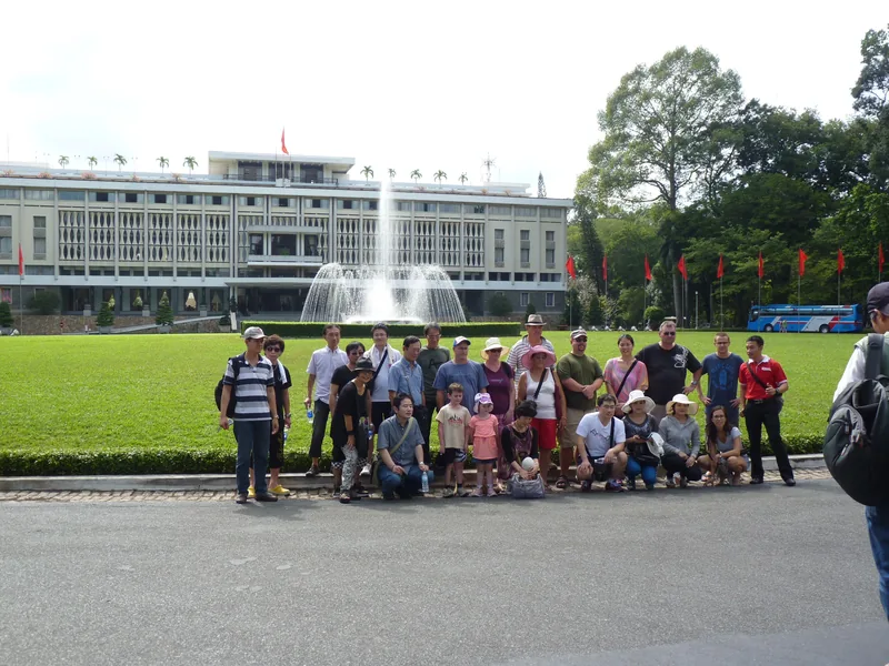 A tour group poses on the lawn in front of the Independence Palace fountain in Saigon.