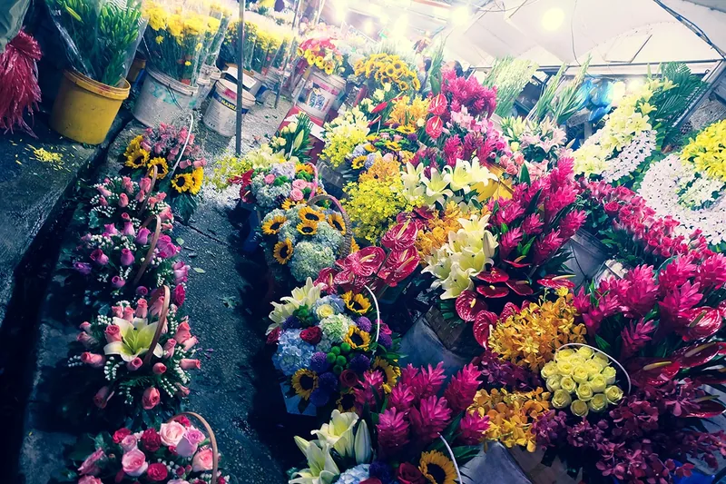 Colorful bouquets of roses, lilies, and sunflowers line a bustling flower market stall in Saigon.