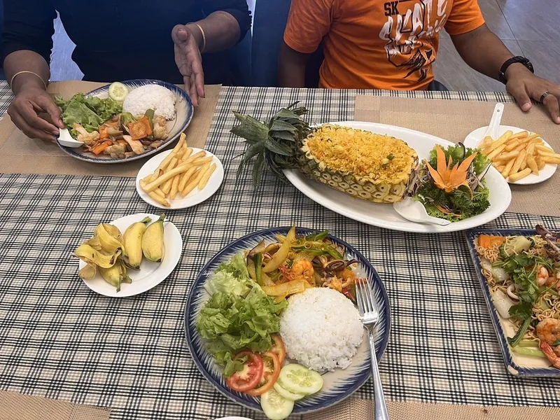 A table in Saigon set with pineapple fried rice, seafood, rice plates, fries, and bananas.