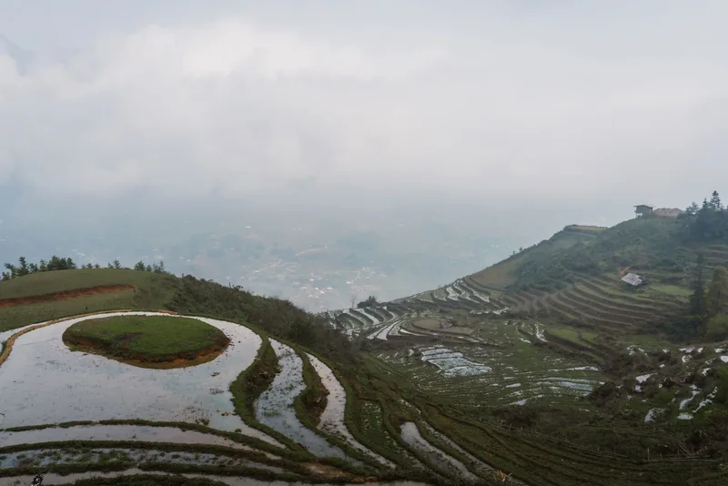 Water-filled rice terraces spiral down misty mountainsides above the valley near Sapa.
