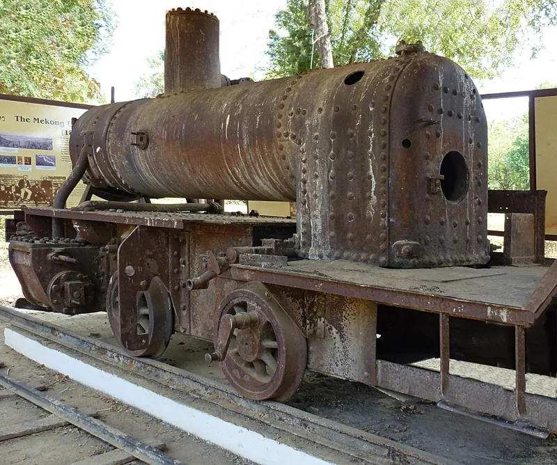 A rusted historic steam locomotive boiler sits on display tracks in Don Khon, Si Phan Don.