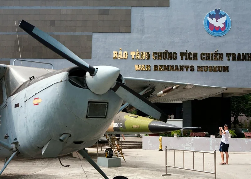 A vintage aircraft and bomb exhibit stand outside the War Remnants Museum facade in Ho Chi Minh City.