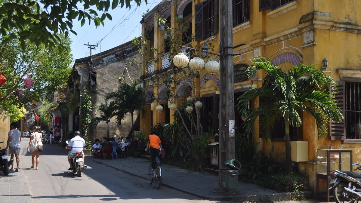 Yellow colonial buildings with paper lanterns line a quiet street in Hoi An's ancient town.