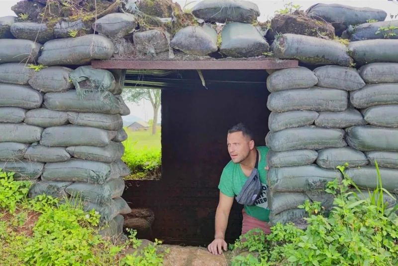 A tourist emerges from a sandbag bunker entrance at a former military site on the Hue DMZ tour.