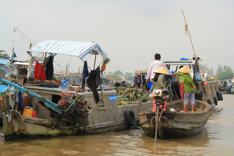 Vendors on wooden boats trade fruit at Cai Rang floating market near Can Tho on the Mekong Delta river.