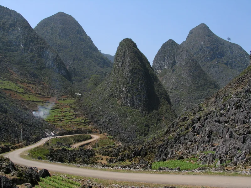 A winding road curves through pointed karst limestone peaks in the Ha Giang mountains of Vietnam.