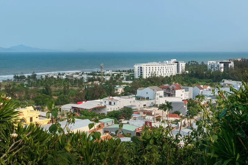 Elevated view over Da Nang's coastal town with rooftops, hotels and a curving beach against the sea.