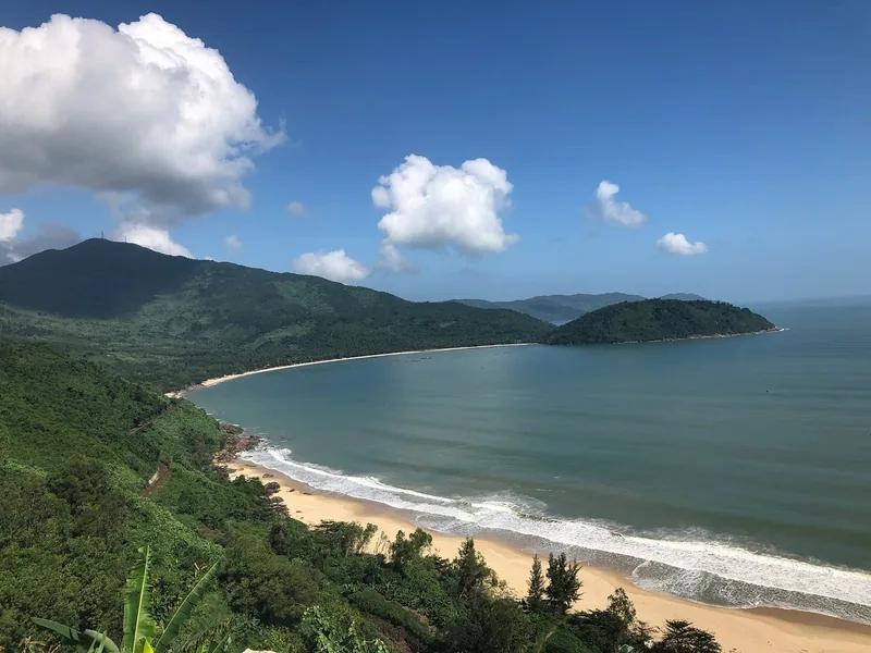 A curving sandy beach and forested mountains meet the sea near the Hai Van Pass in central Vietnam.