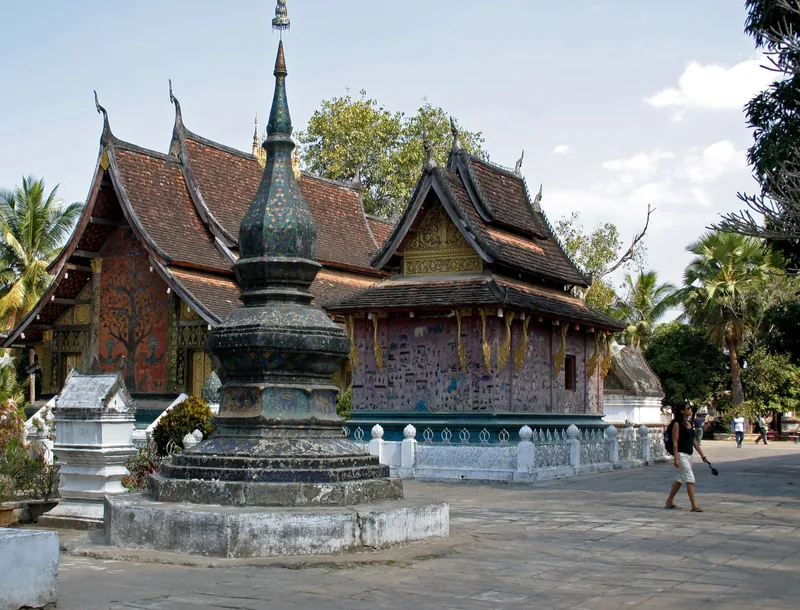 Ornate mosaic-covered stupa and multi-tiered roofs of Wat Xieng Thong temple in Luang Prabang, Laos.