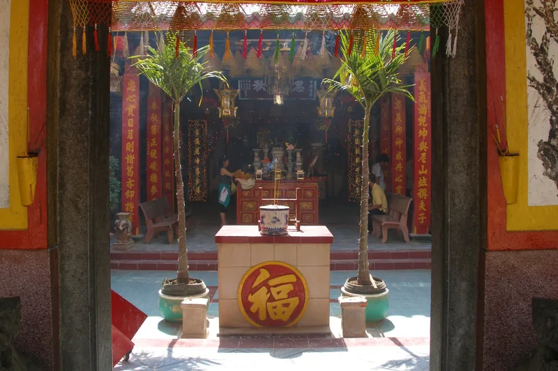 A courtyard temple in Chau Doc with red couplets, an incense altar and potted palms framed by the entrance.