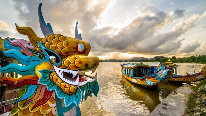 Colorful carved dragon boats moored on the Perfume River in Hue under a dramatic cloudy sky.